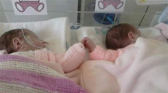 صورة: رضيعتان توأم تمسكان أيدي بعضهما
