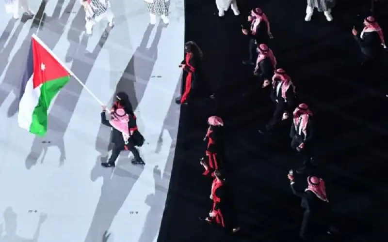 لاعبان يحملان علم الأردن في افتتاح