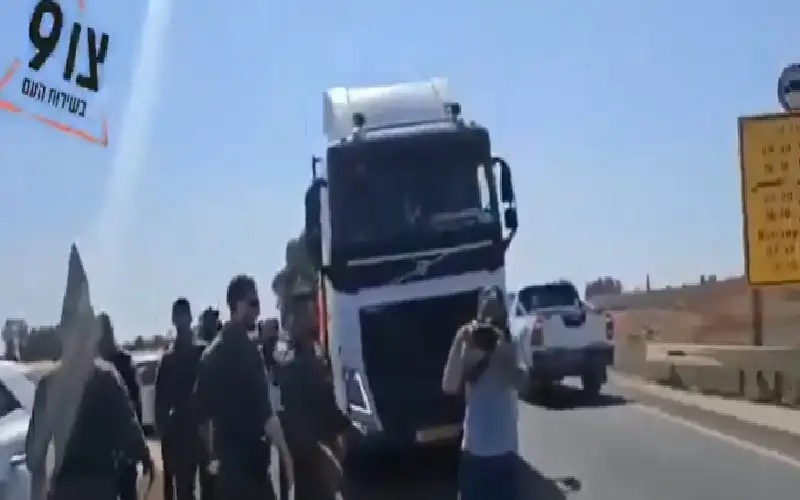 مستوطنون إسرائيليون يقفون أمام شاحنات المساعدات