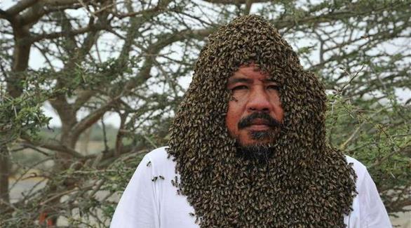 سعودي يغطي وجهه بمئات النحل دون