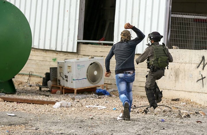 صورة فلسطيني يلاحق جندي بالحجارة تشعل